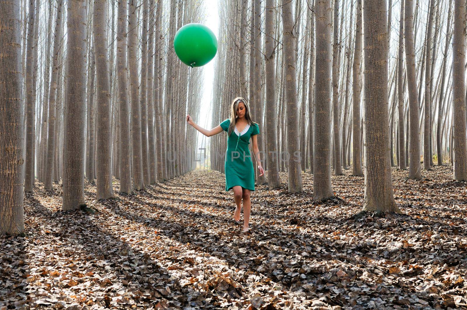 Beautiful blonde girl, dressed in green, walking into the forest by javiindy