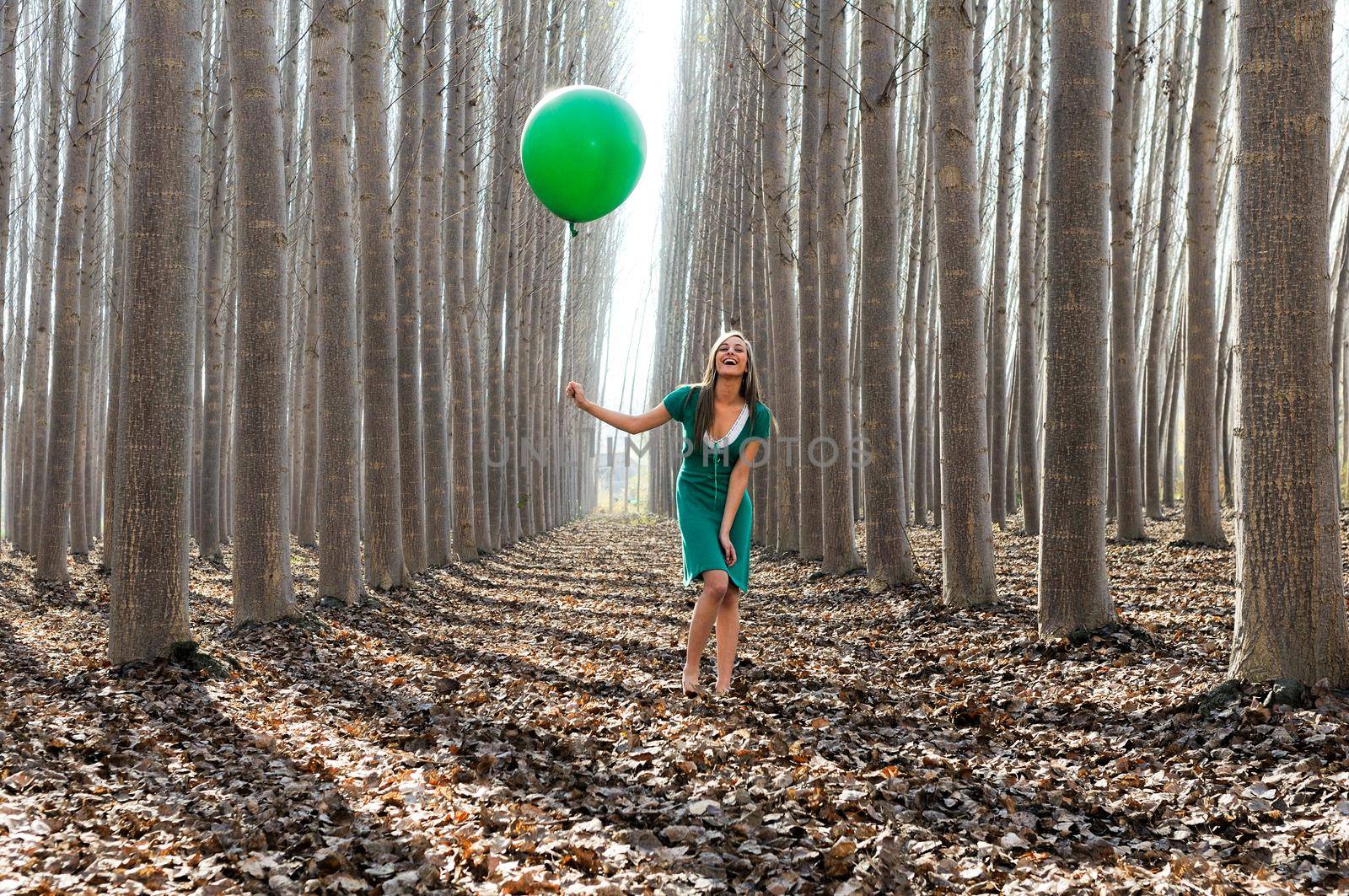 Beautiful blonde girl, dressed in green, laughing in the forest