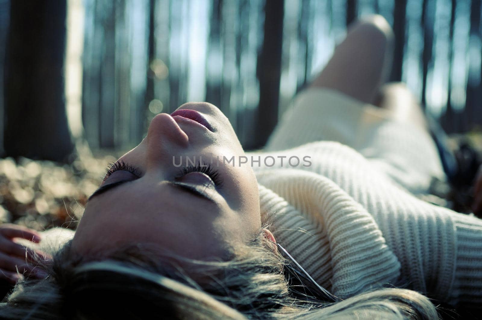Beautiful blonde girl lying on leaves in a forest of poplars