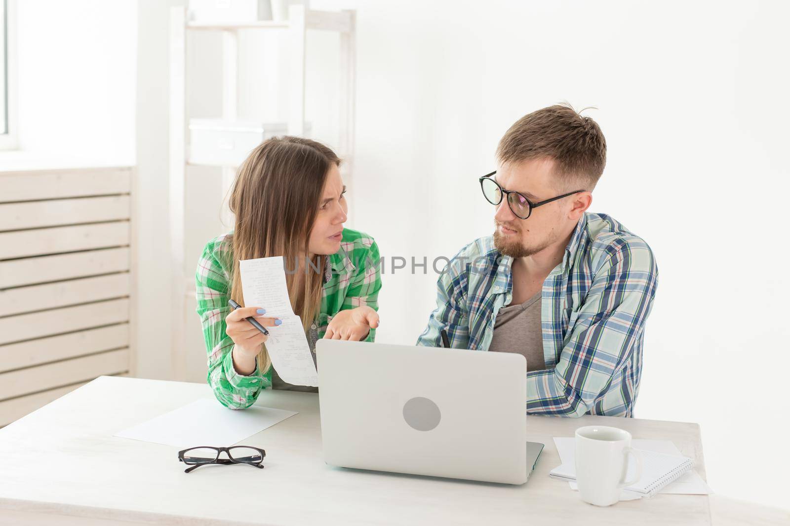 Husband and wife discuss amount in check for payment of the apartment and compare it with the rates on official website while sitting at the table with laptop. Concept of payment of utility bills. by Satura86