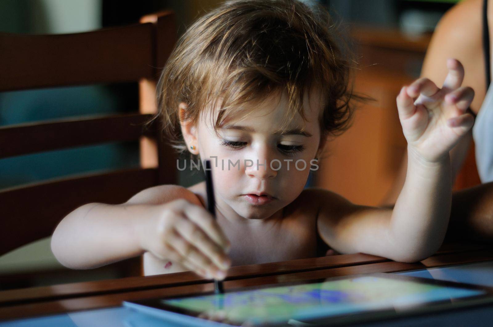 Little girl painting with a digital tablet at home. by javiindy