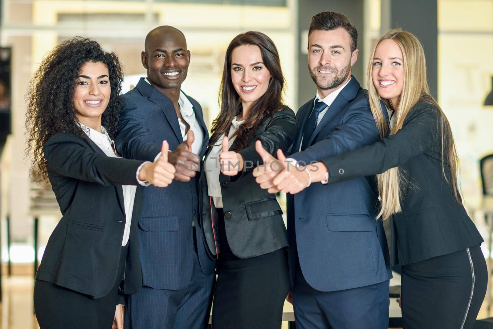 Group of businesspeople with thumbs up gesture in modern office. by javiindy