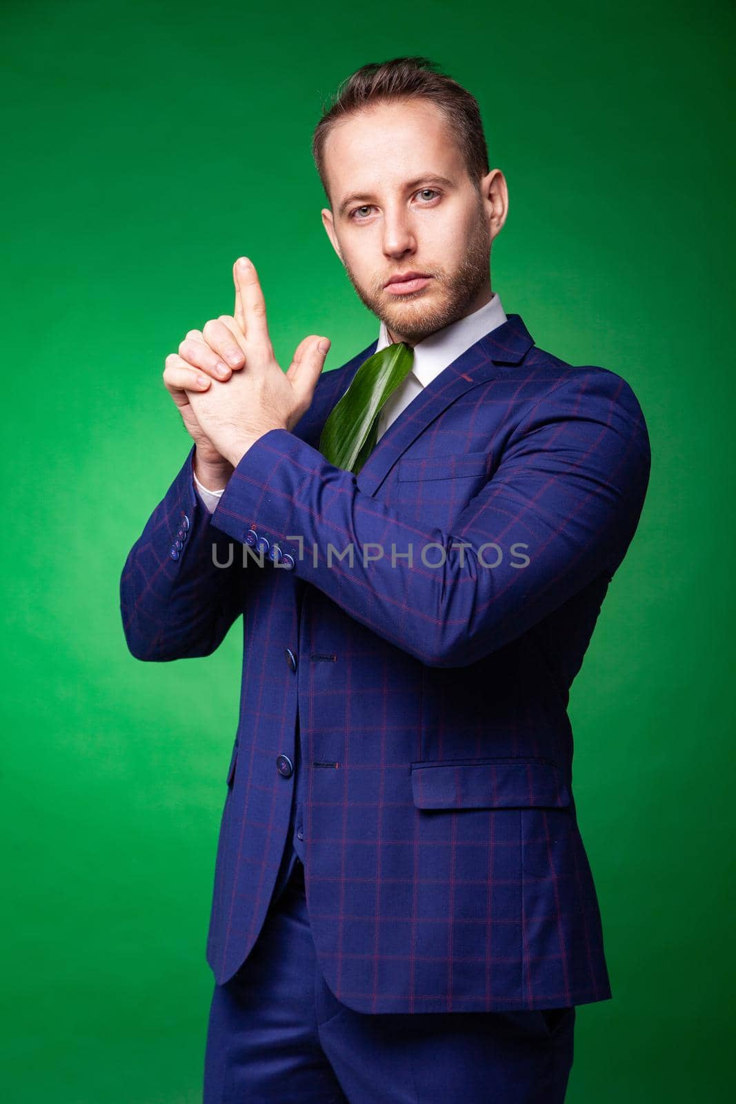 Self confident businessman in green leaf tie pointing at camera by Julenochek