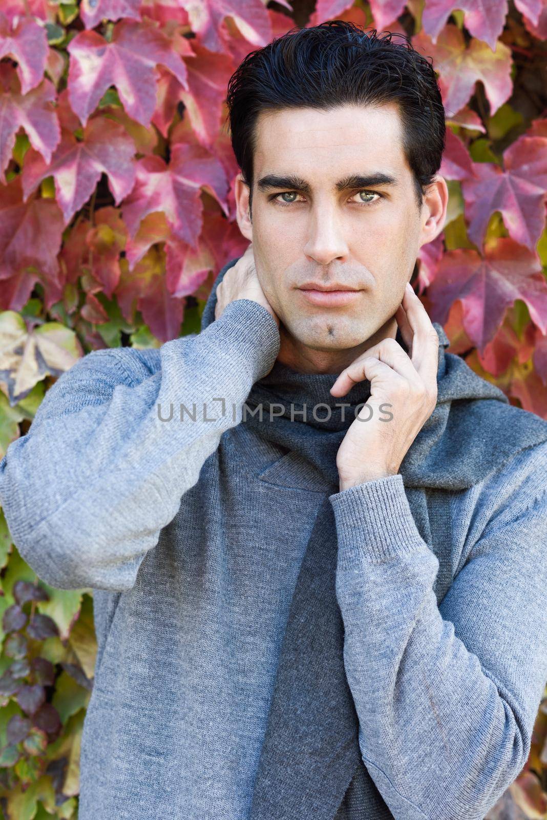 Handsome man wearing winter clothes in autumn leaves background by javiindy