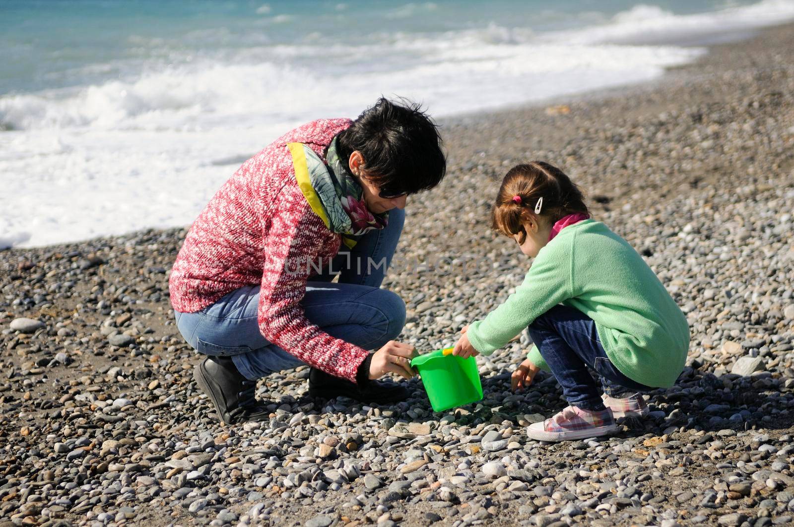 Mother and little girl having fun on the beach in winter by javiindy