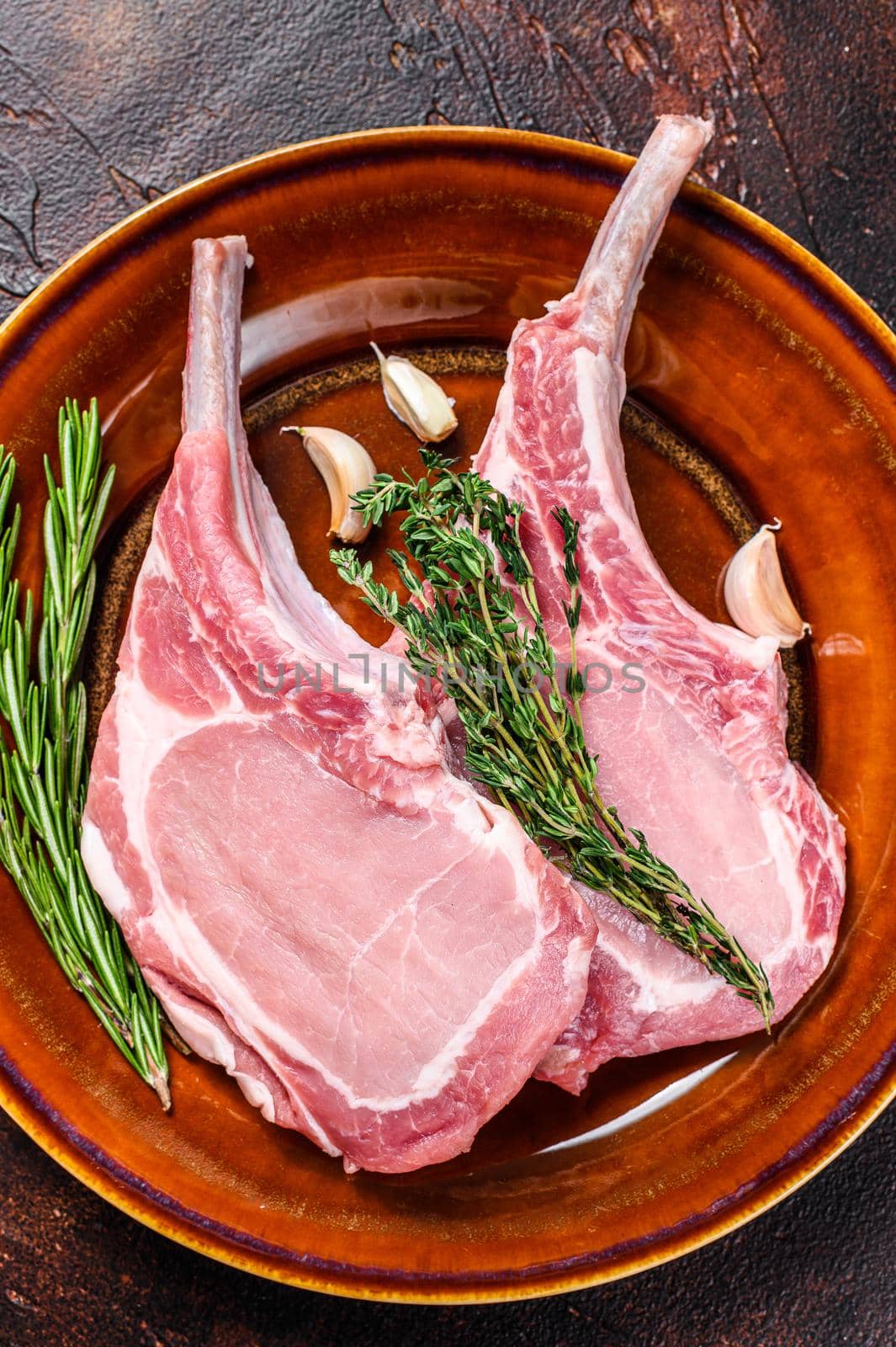 Raw pork chops meat steaks with pepper and salt. Dark background. Top view.