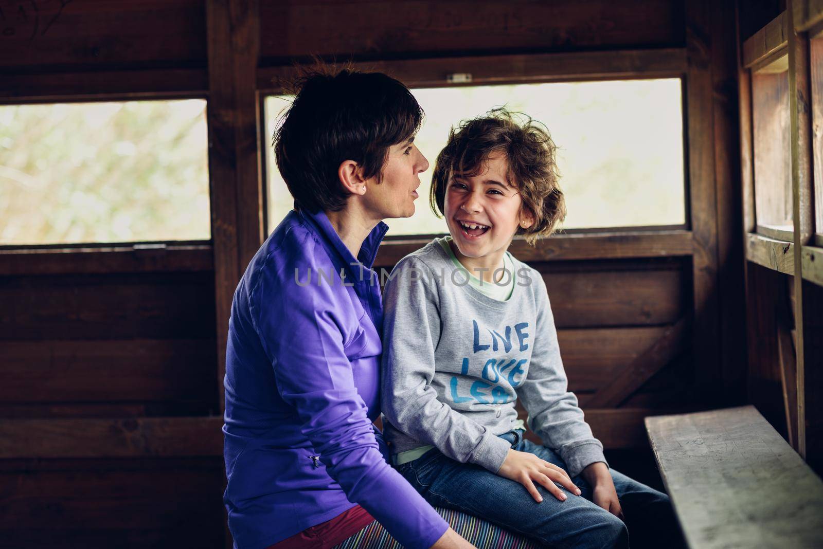 Mother with her seven year old daughter laughing in a cabin in the countryside by javiindy