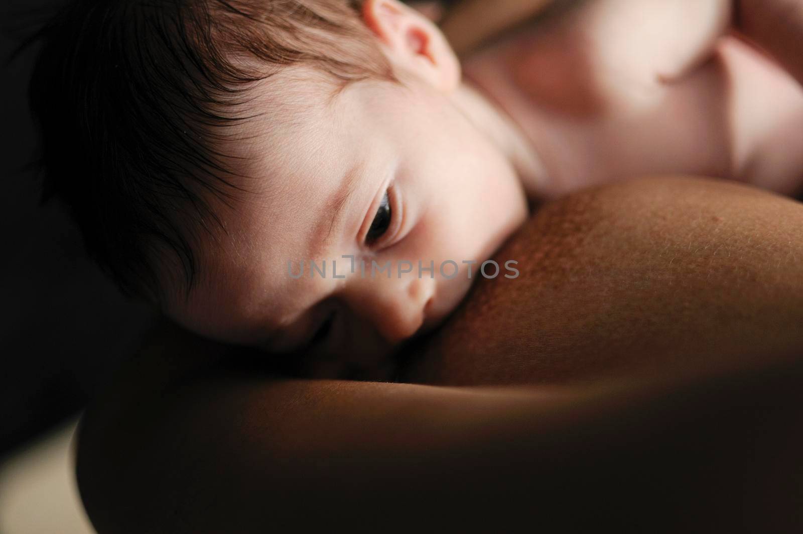 Young mother breastfeeding newborn baby 2 months old at home