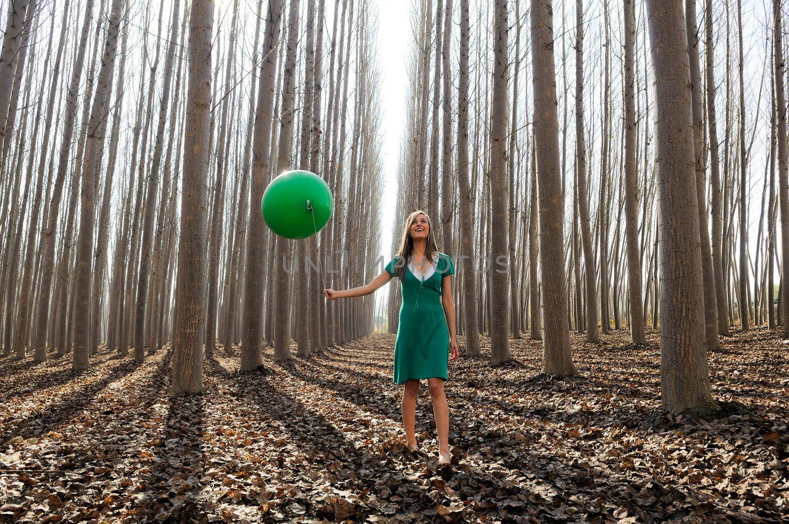 Beautiful blonde girl, dressed in green, walking into the forest