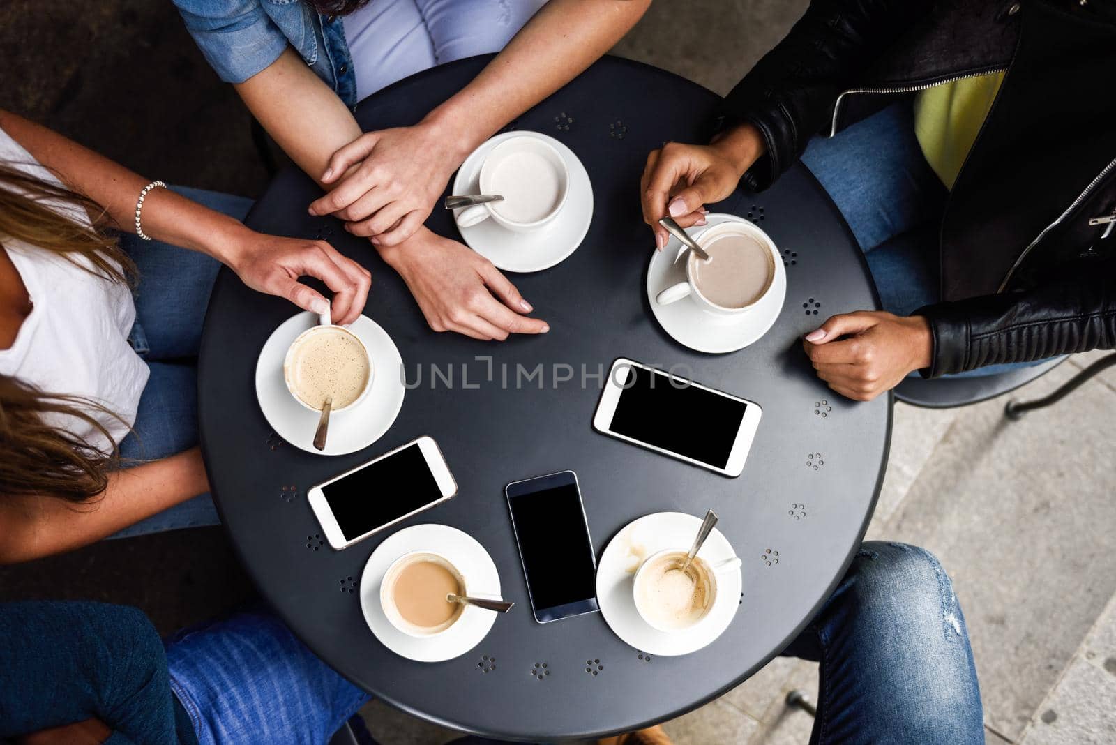 Top view of hands with coffee cups and smartphones on table in a urban cafe.