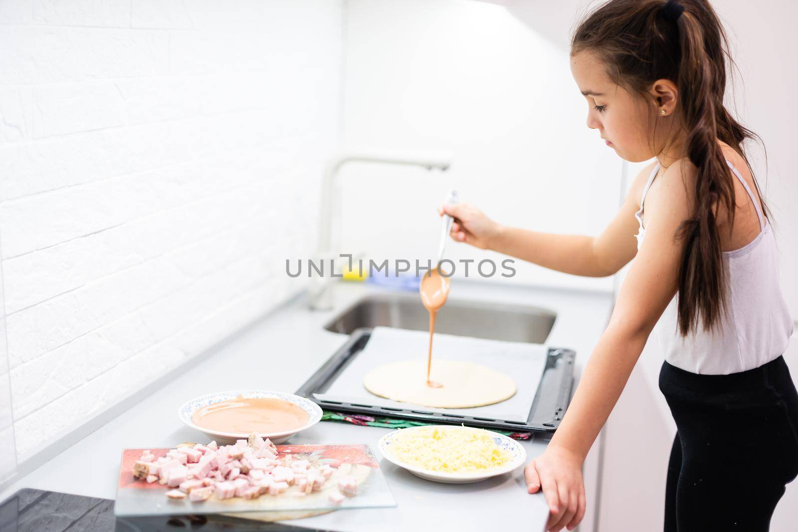 little girl makes pizza at home