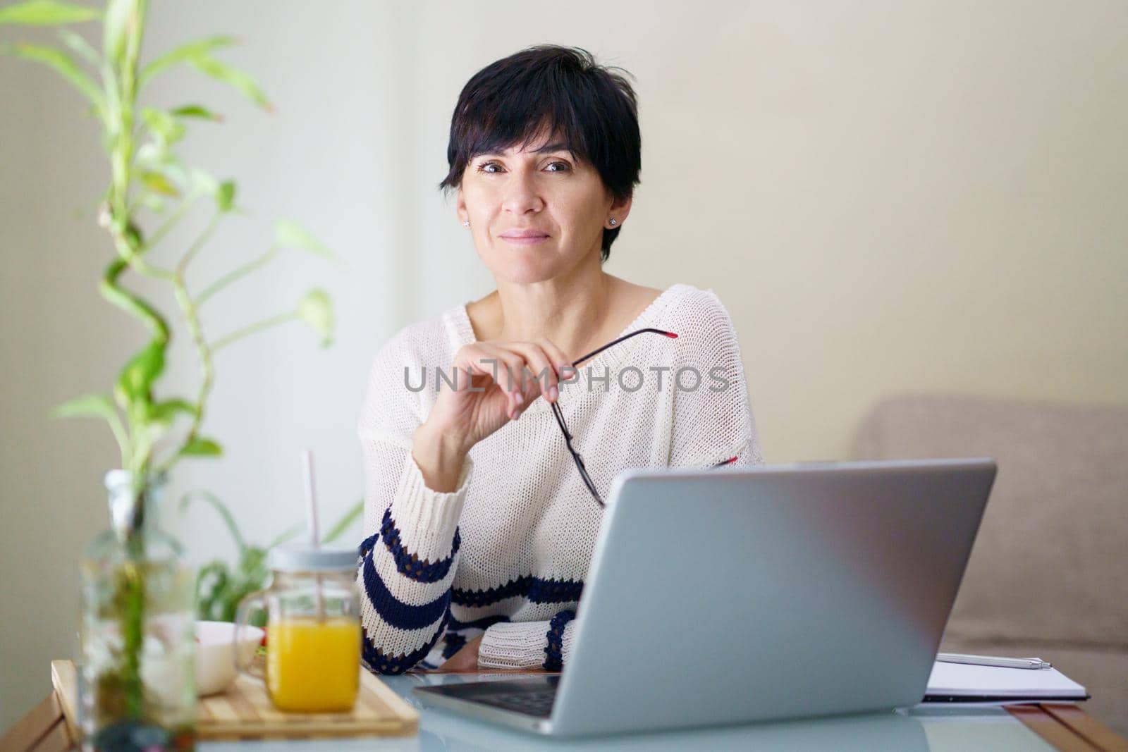 Smiling woman teleworking from home with her laptop. Female in her 50s