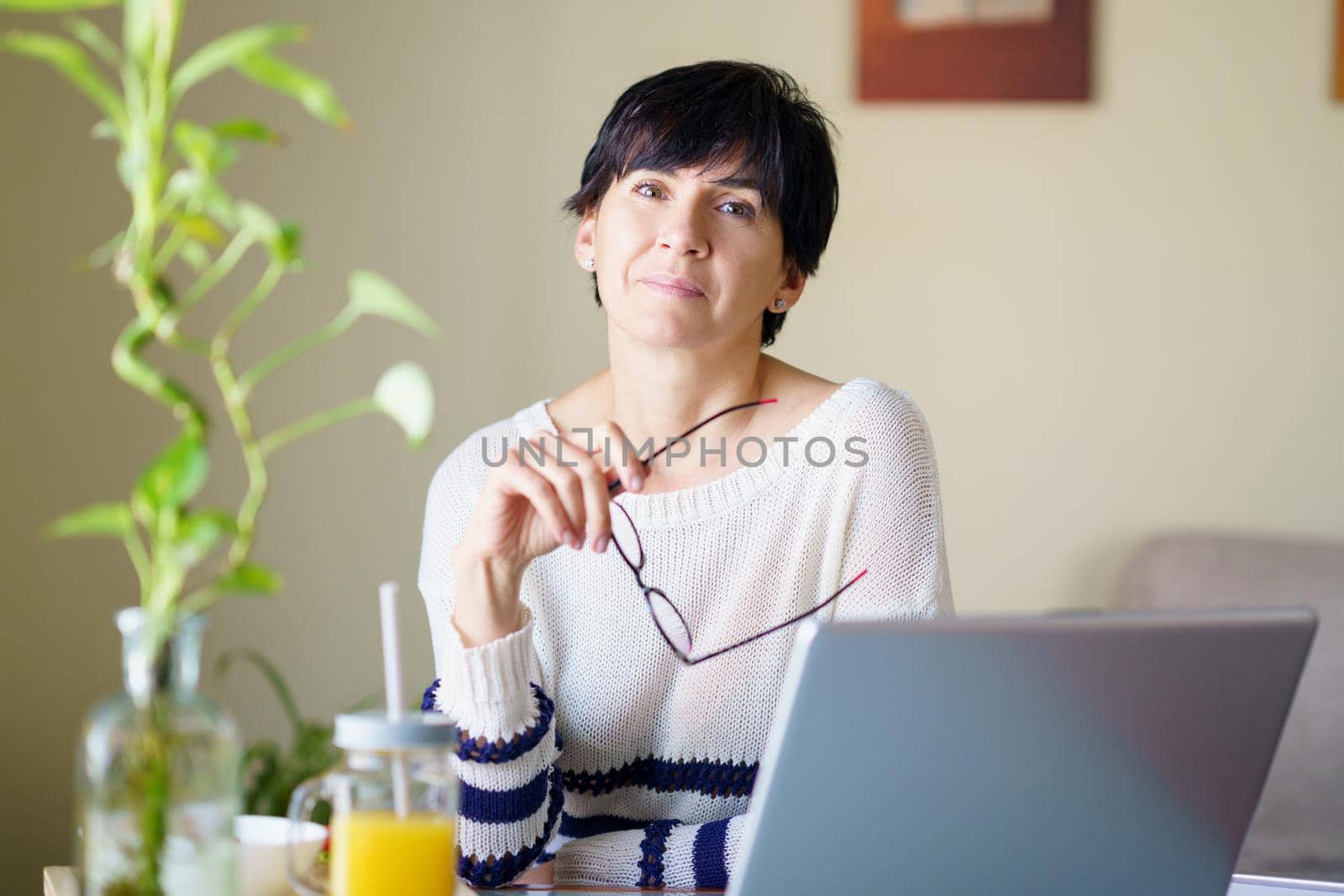 Woman teleworking from home with her laptop. Female in her 50s