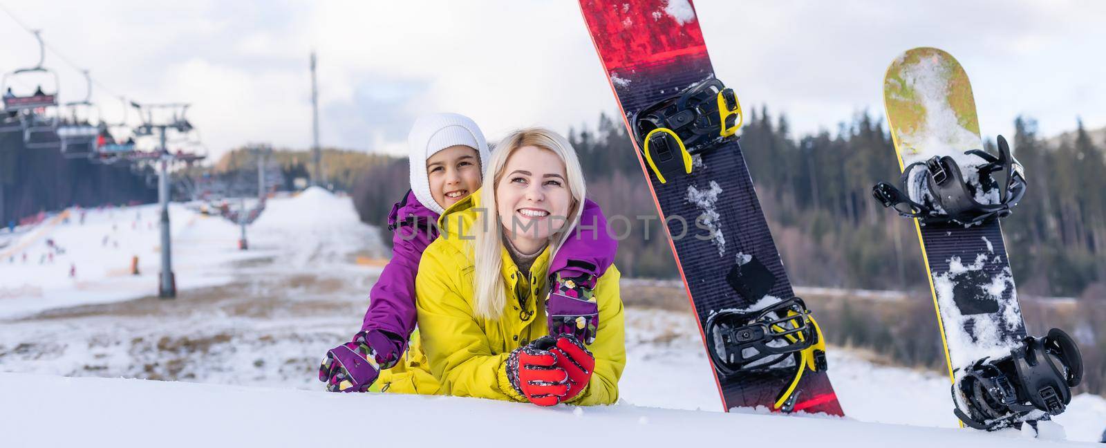 mother and daughter with snowboards in a mountain resort
