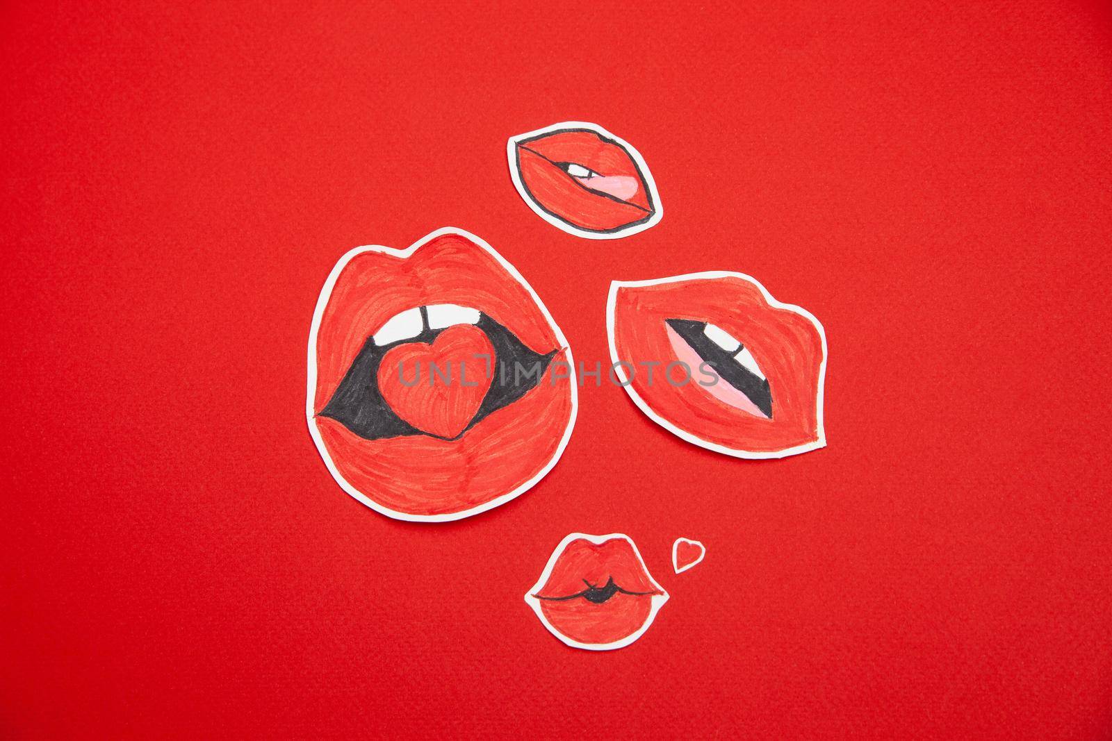 From above shot various painted female lips shaped stickers scattered on red background