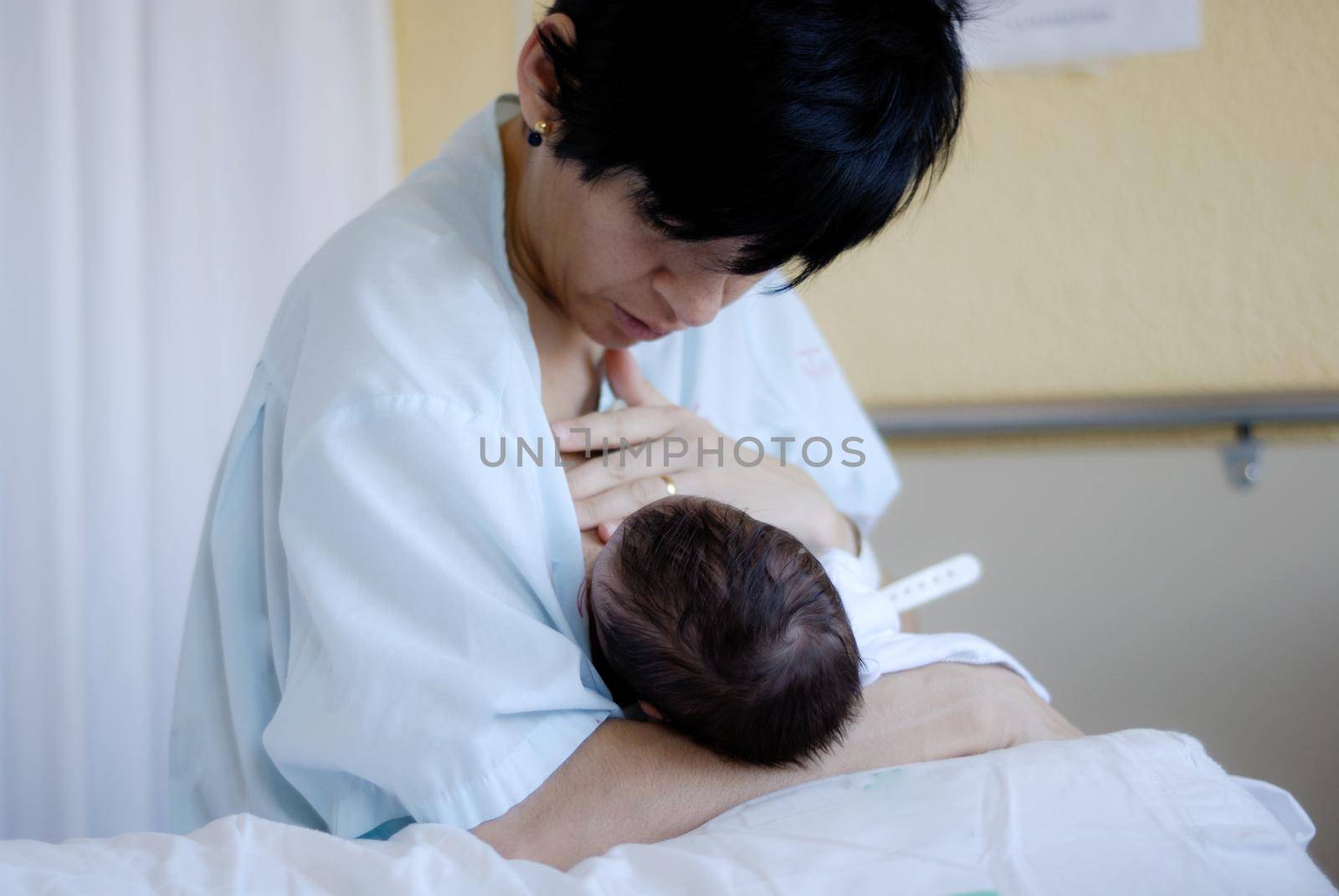 Young mother feeding breast her newborn baby at the hospital.