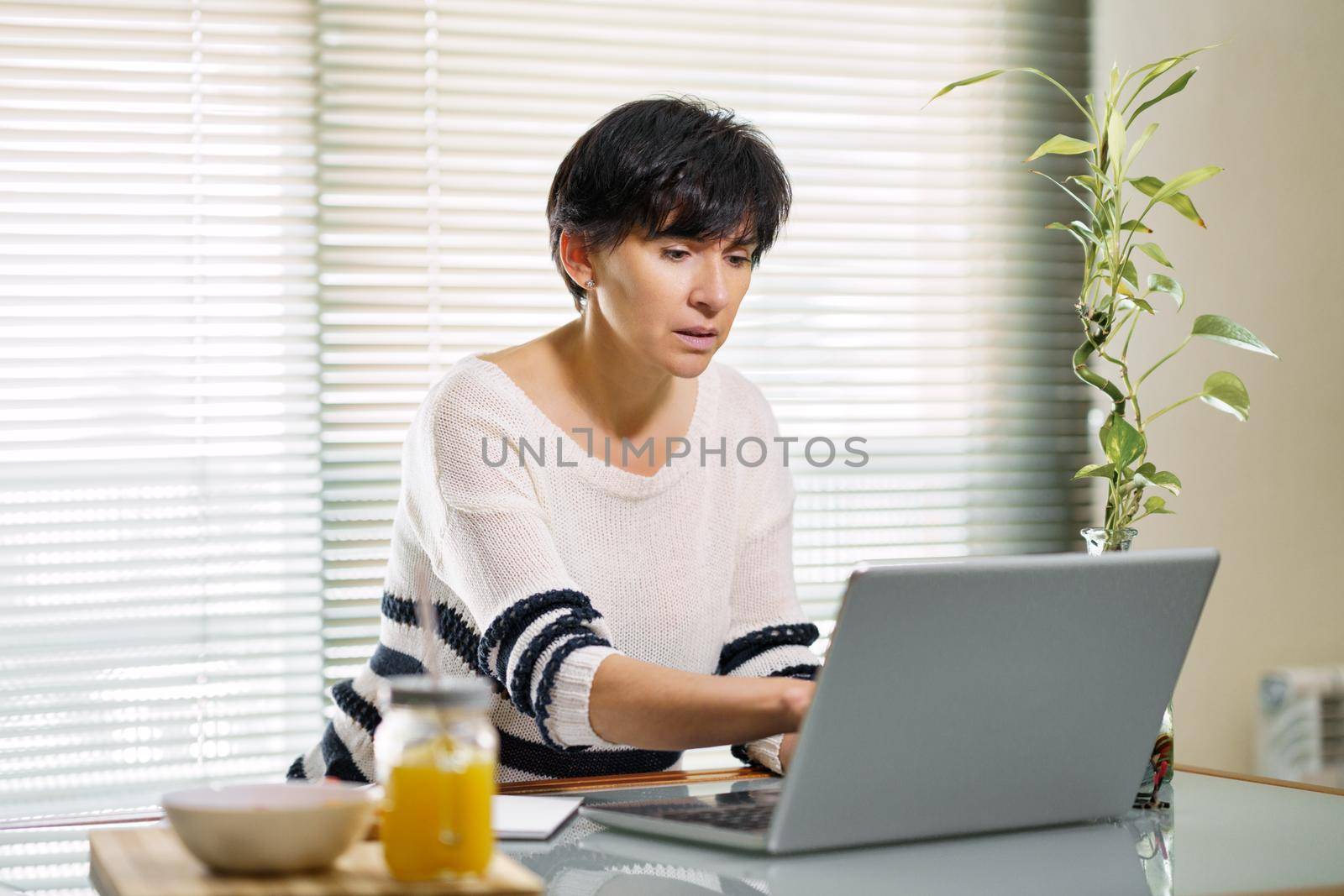 Woman teleworking from home with her laptop. by javiindy