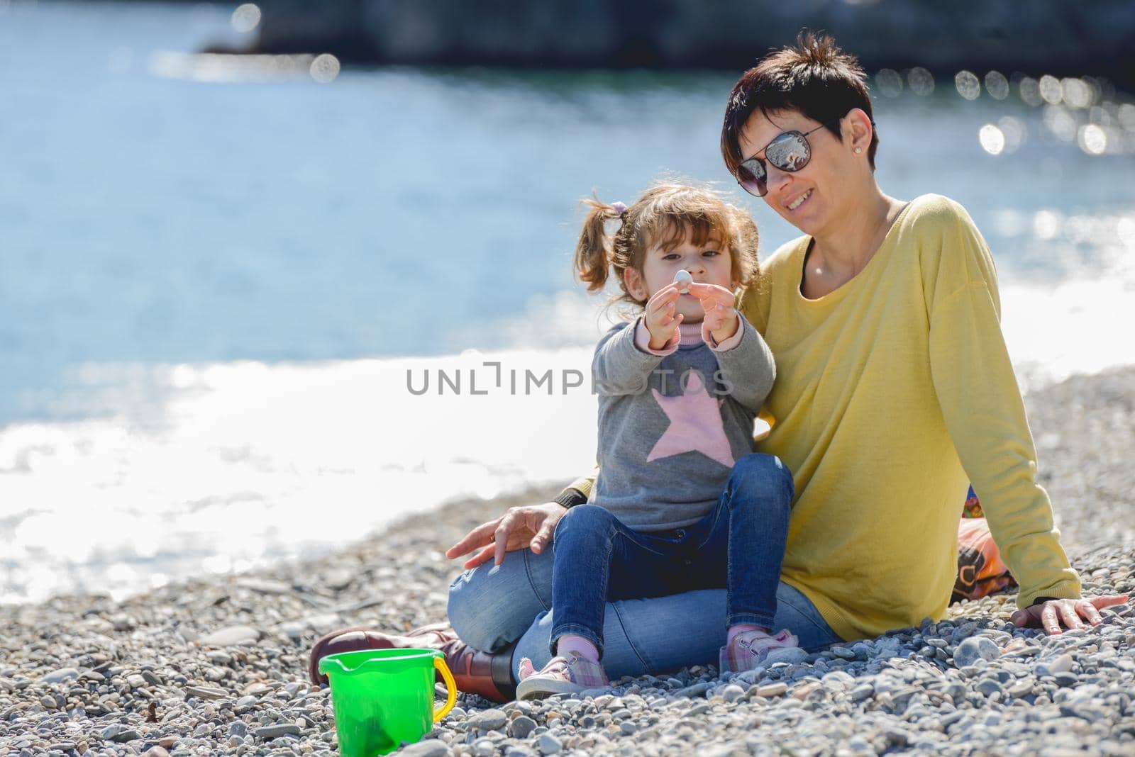 Portrait of mother and her little daughter having fun on the beach