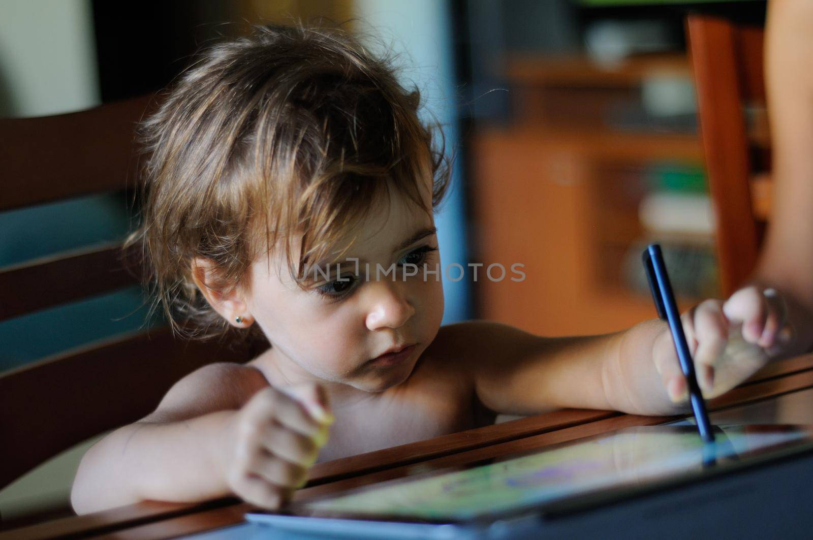 Little girl, two years old, painting with a digital tablet at home.