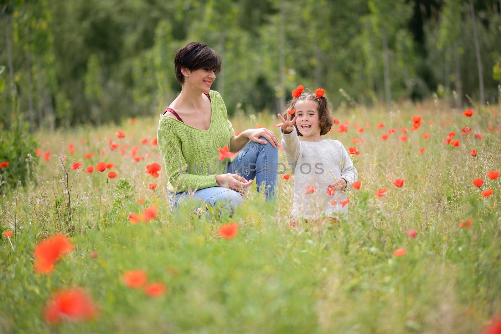 Mother with her little daughter in poppy field by javiindy