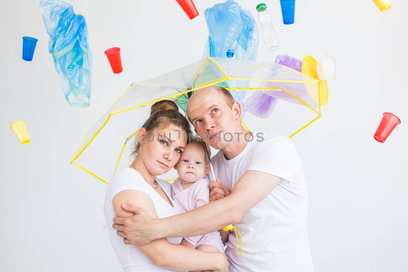 Environmental pollution, plastic recycling problem and waste disposal concept - surprised family under garbage on white background. by Satura86