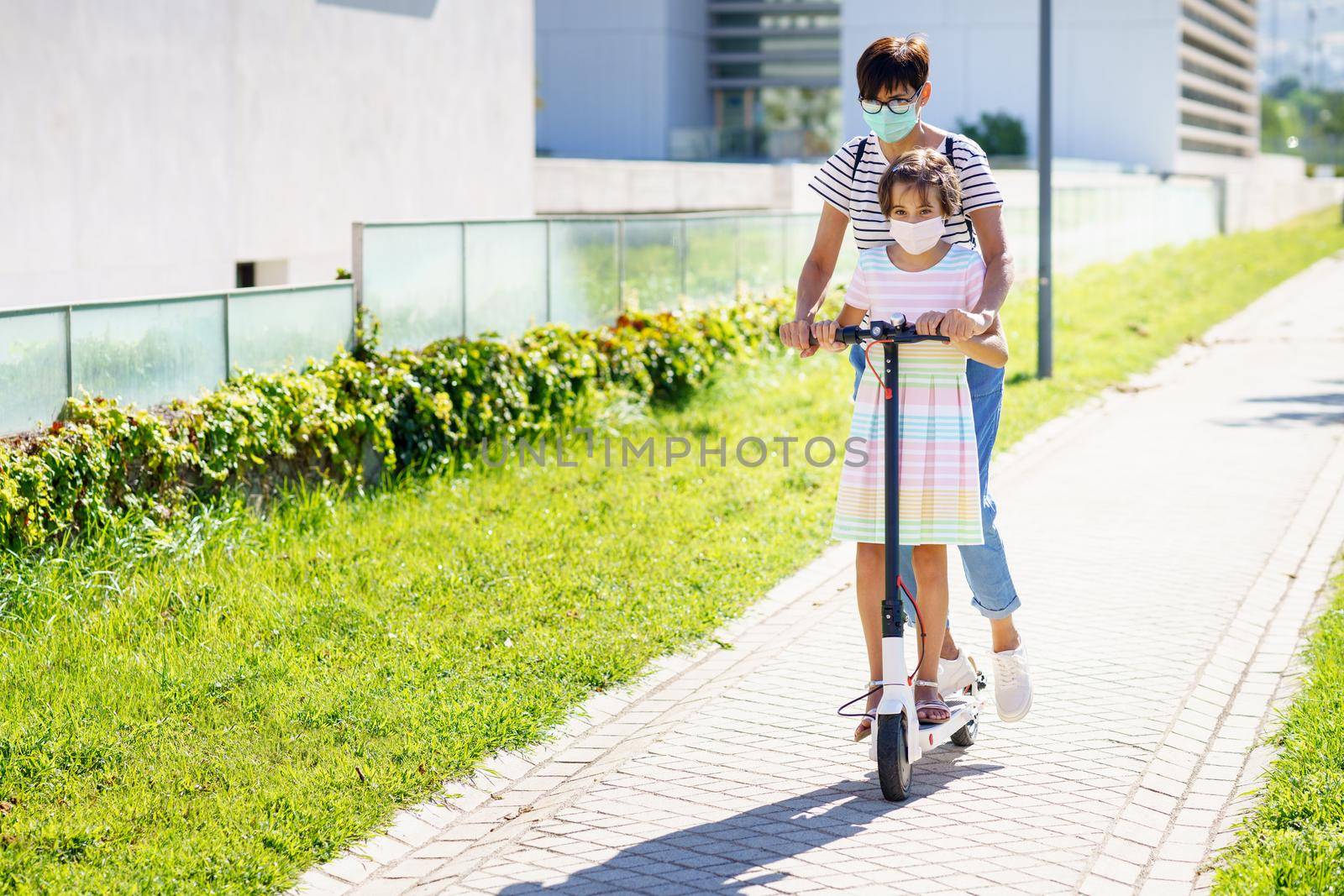 Mother and daughter riding on electric scooter. by javiindy