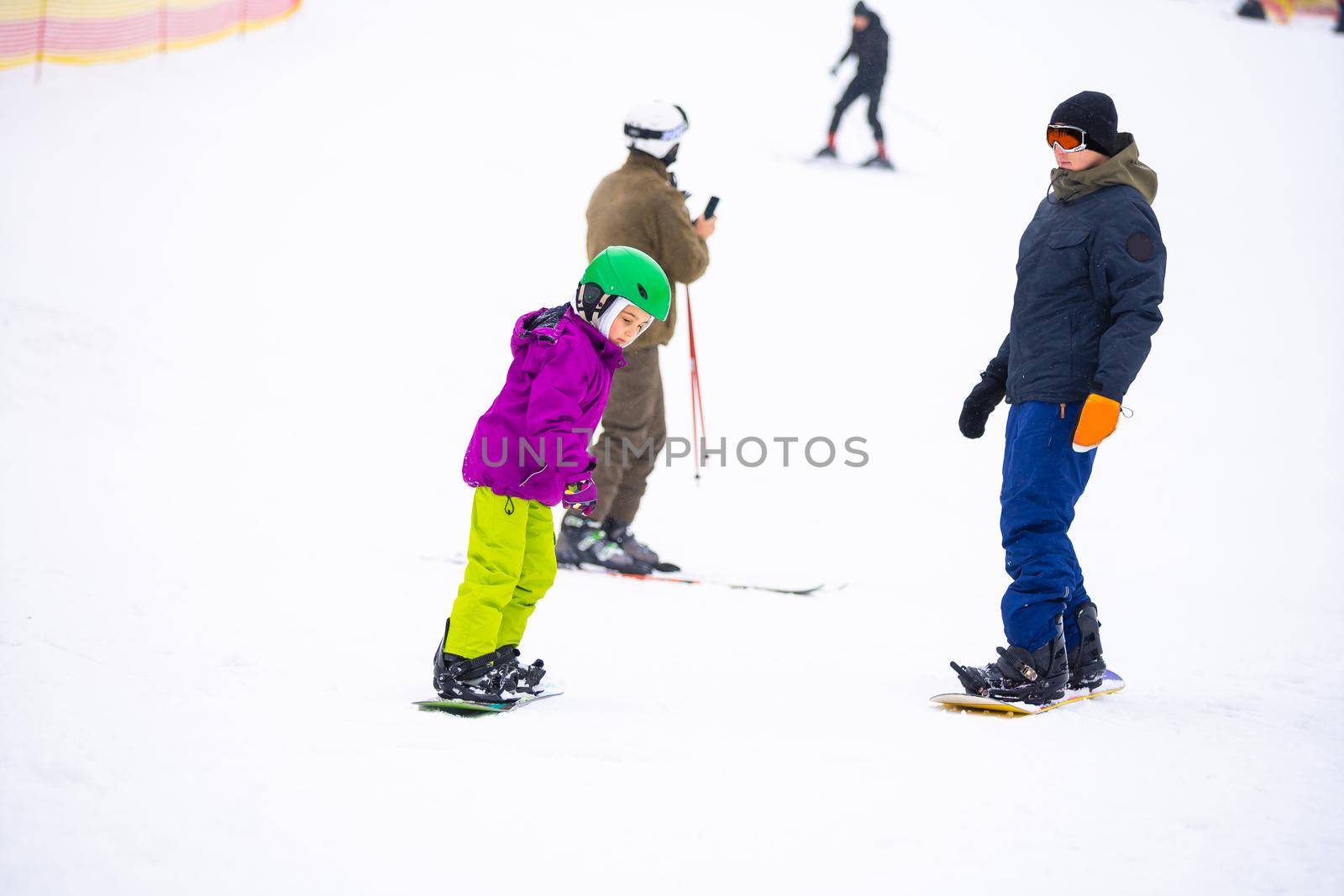 Snowboard Winter Sport. little girl learning to snowboard, wearing warm winter clothes. Winter background. by Andelov13