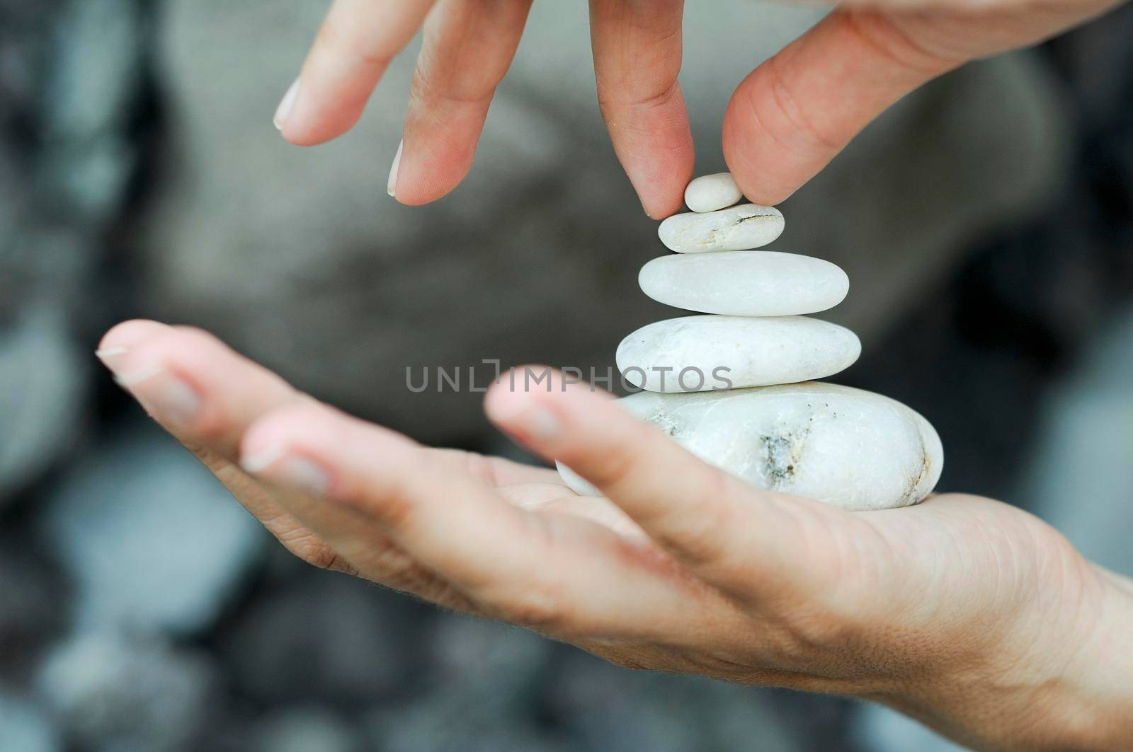 White stones stacked in a woman's hands as a relaxation activity