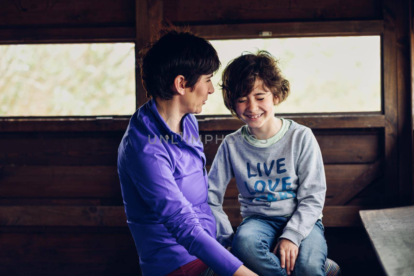 Mother with her seven year old daughter laughing in a cabin in the countryside by javiindy