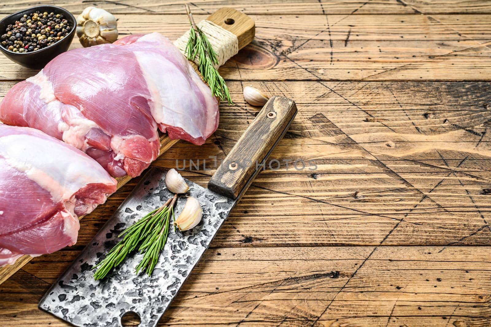 Raw boneless Turkey thigh fillet on a chopping Board. wooden background. Top view. Copy space by Composter