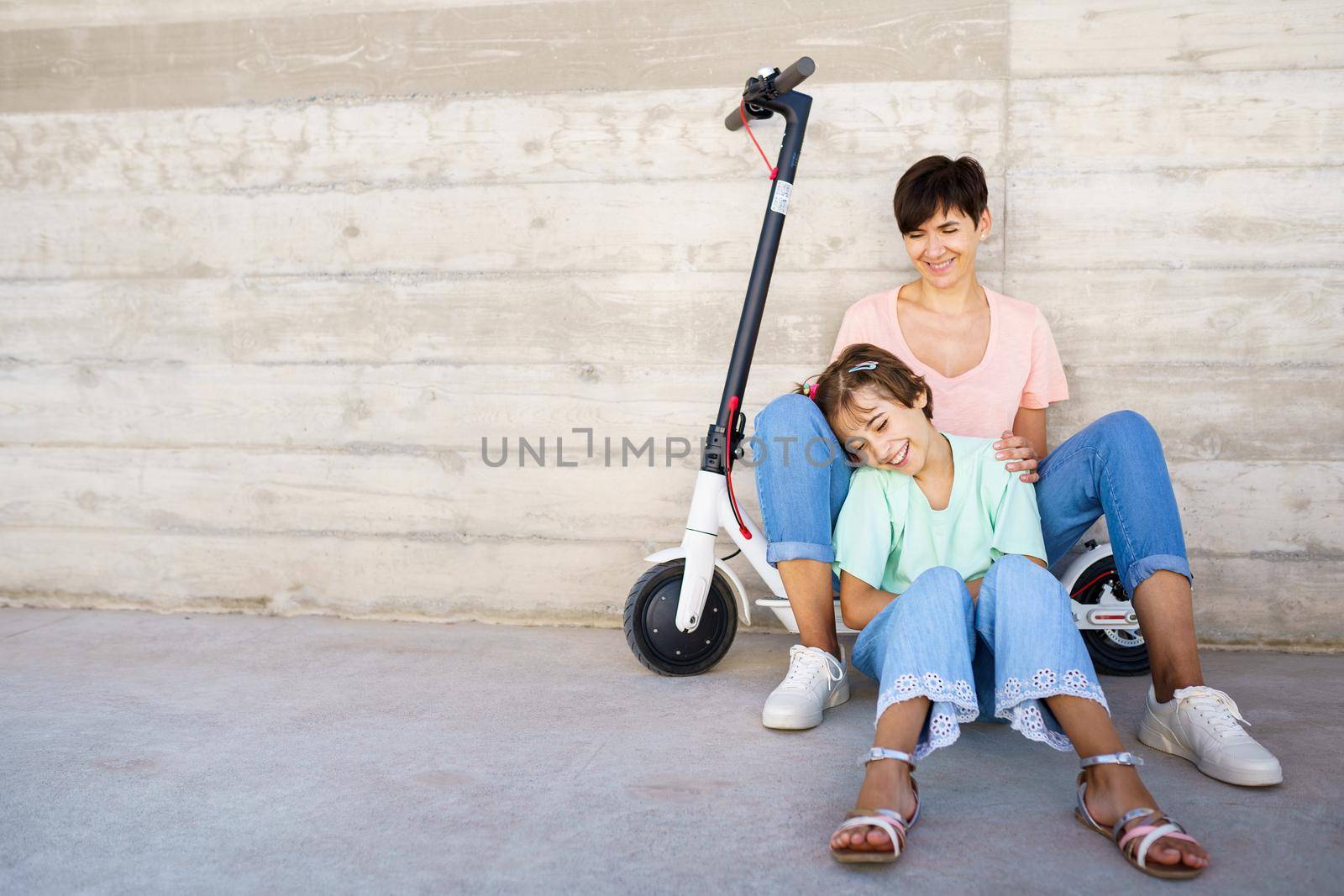 Mother and daughter sitting on an electric scooter by javiindy