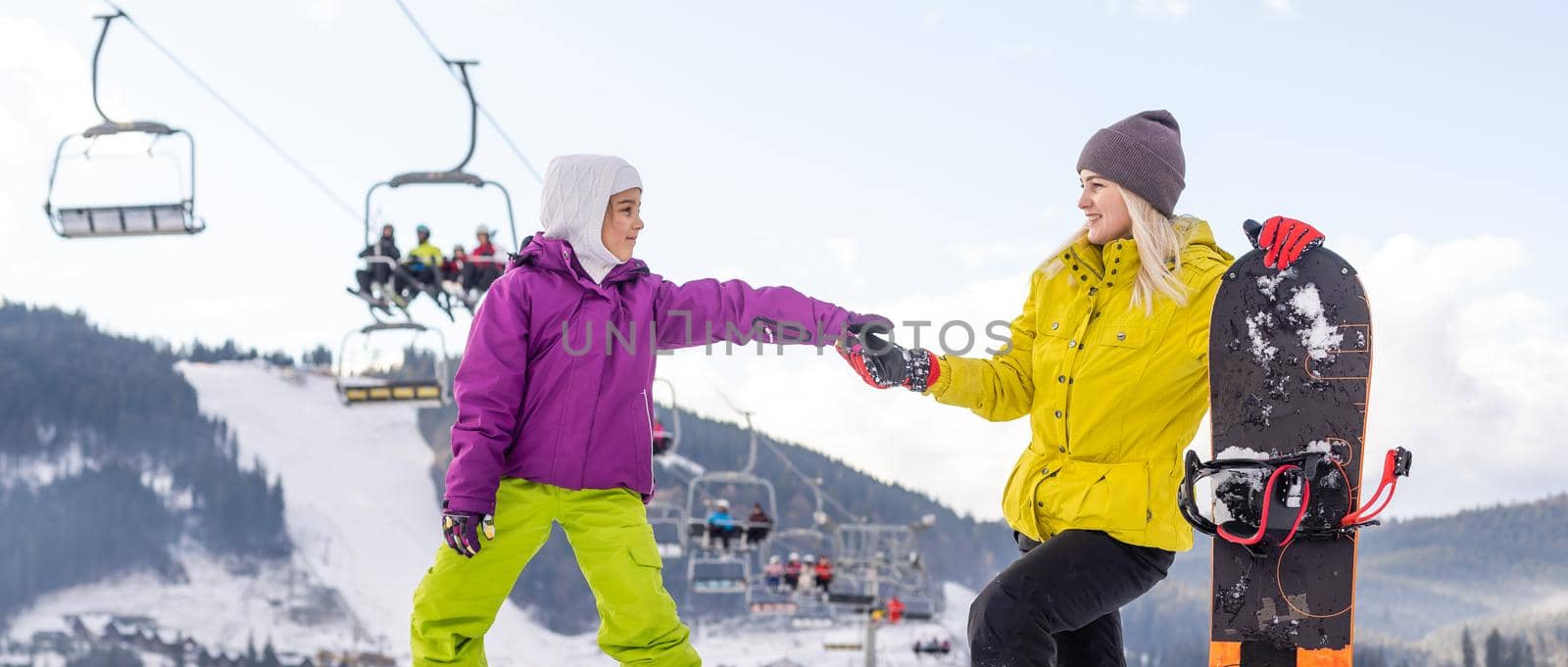 mother and daughter with snowboards at winter resort