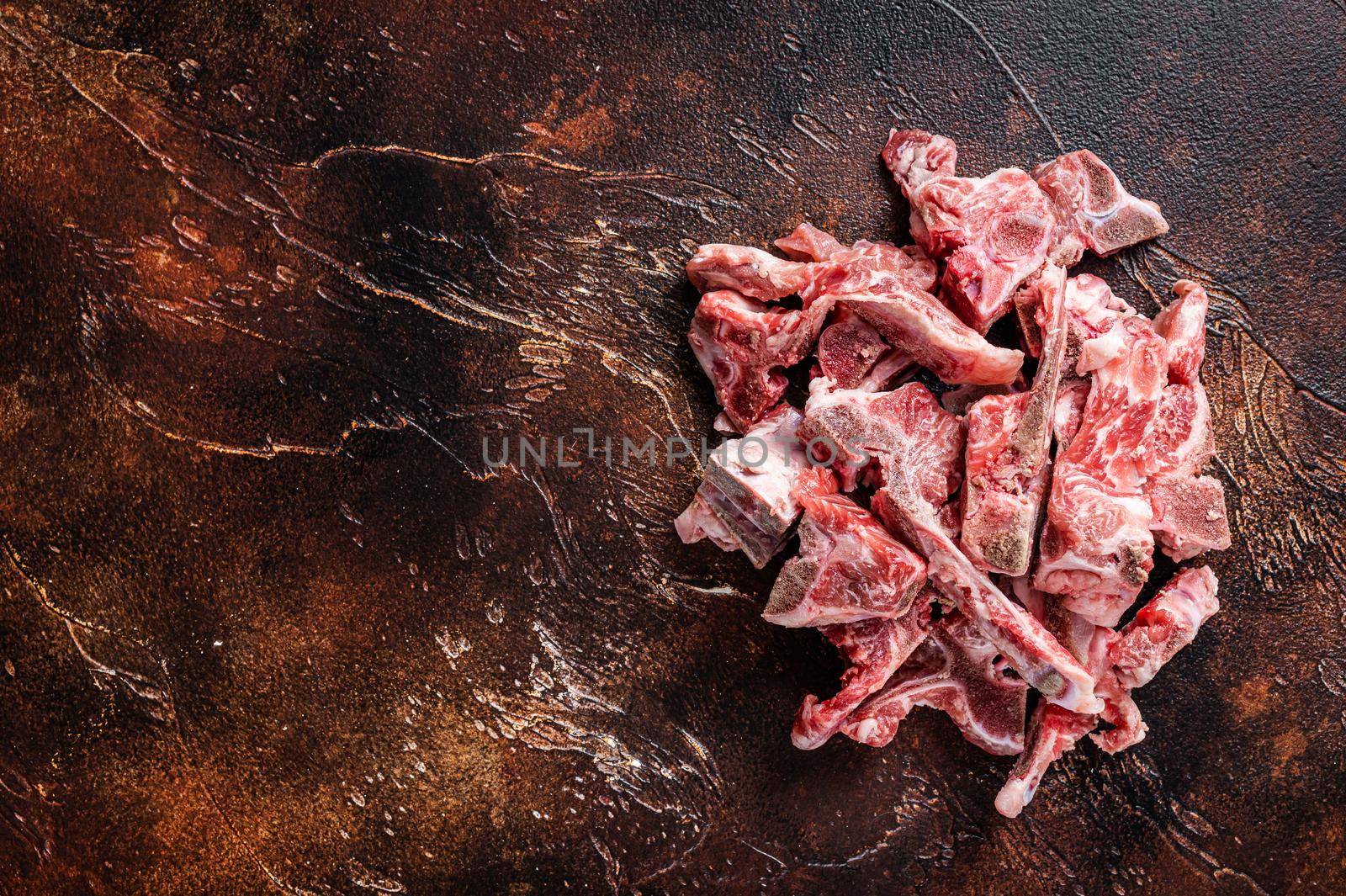Raw meat on the bone diced for stew. Dark background. Top View. Copy space by Composter