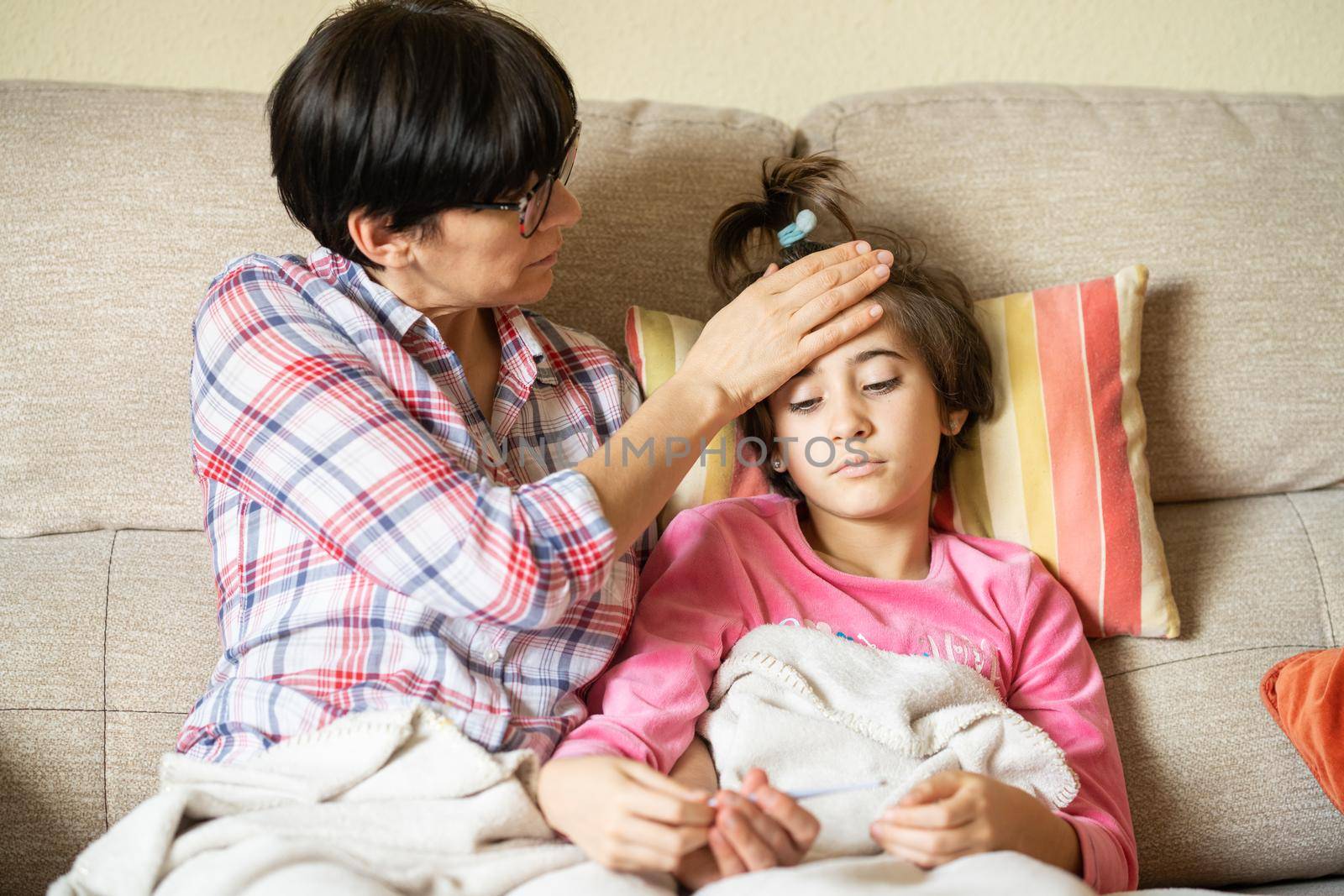 Mother measuring her daughter's temperature with a digital thermometer to check for fever