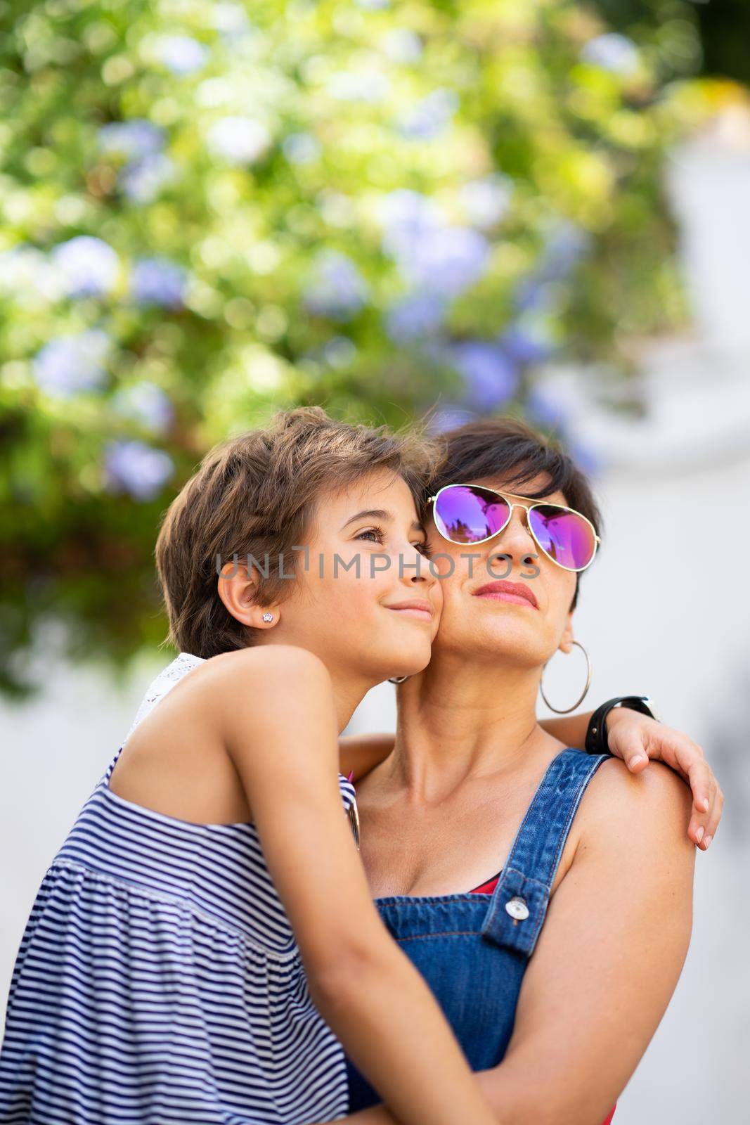 Mother and her little daughter traveling together in urban background. Women wearing sunglasses.