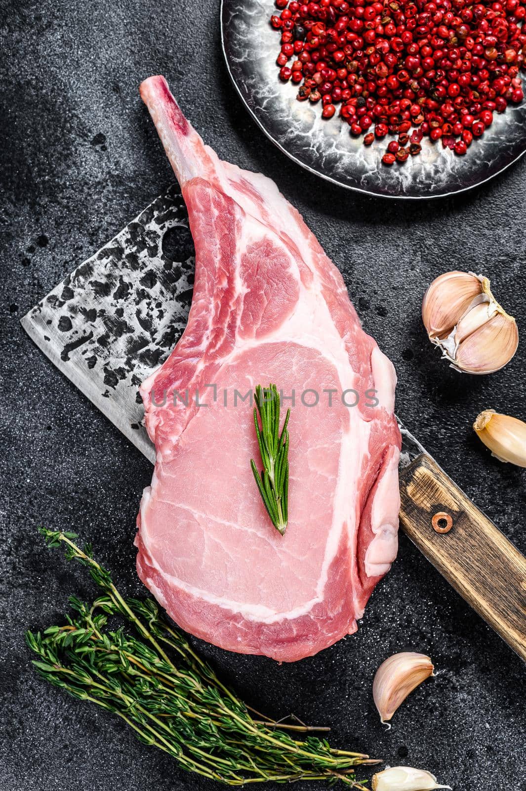 Raw tomahawk pork chop meat steak on a meat cleaver. Black background. Top view by Composter