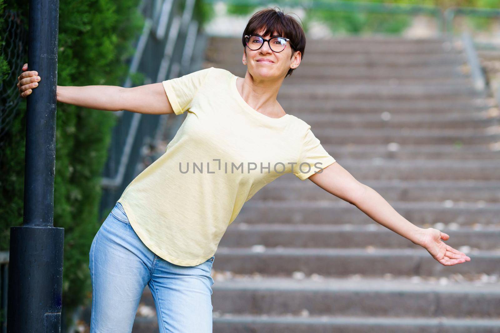 Funny happy middle-aged woman wearing eyeglasses in an urban park.