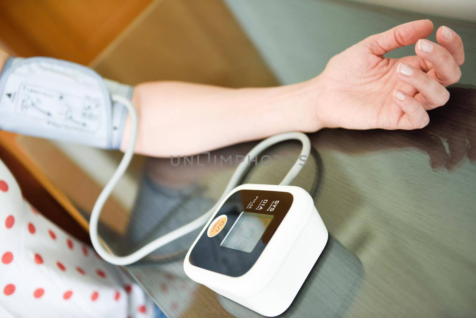 Woman measuring her own blood pressure at home. by javiindy