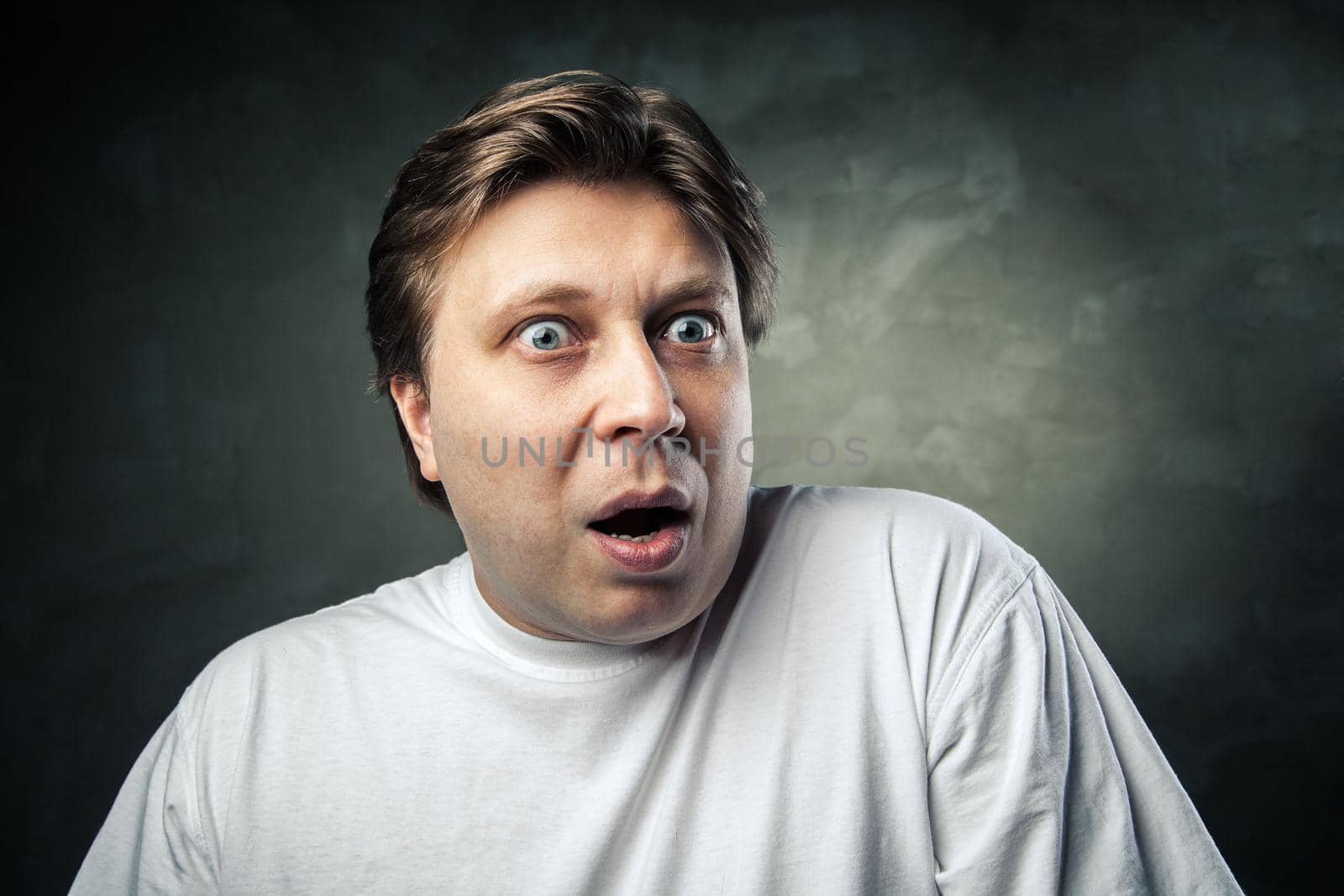 portrait of young beautiful man surprised face expression over gray