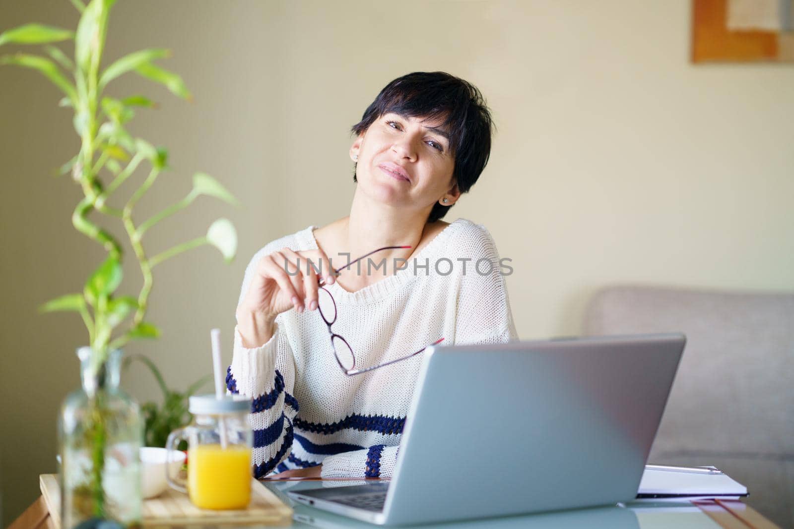 Smiling woman teleworking from home with her laptop. Female in her 50s