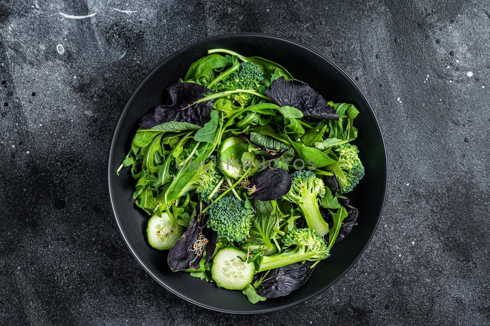 Fresh salad mix of spinach, arugula leaves, chard and lambs lettuce with vegetables. Black background. Top view by Composter