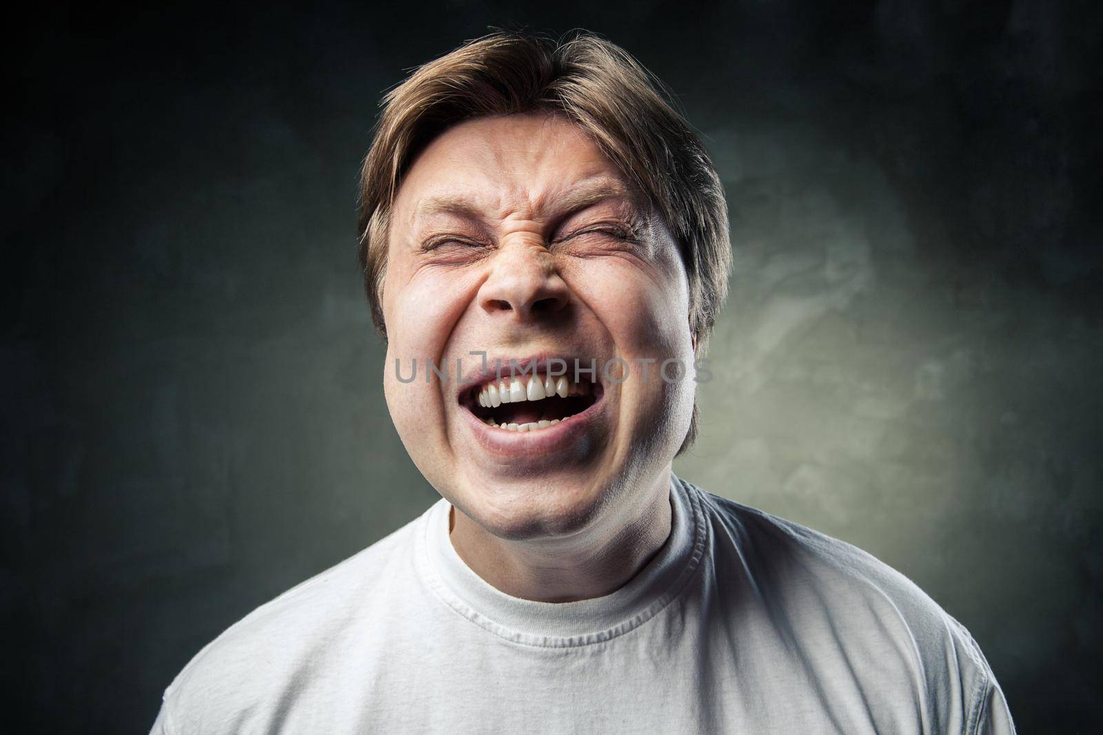 portrait of young angry man over dark grey background