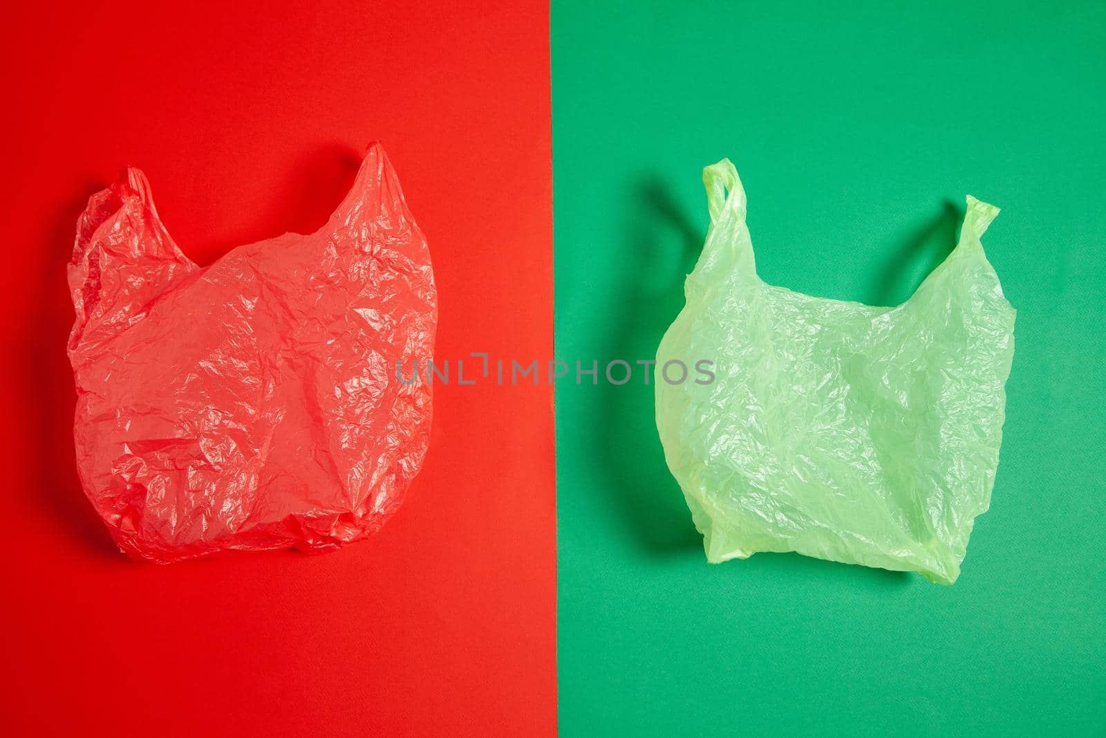 Top view of crumpled red and green plastic bags placed on two color background