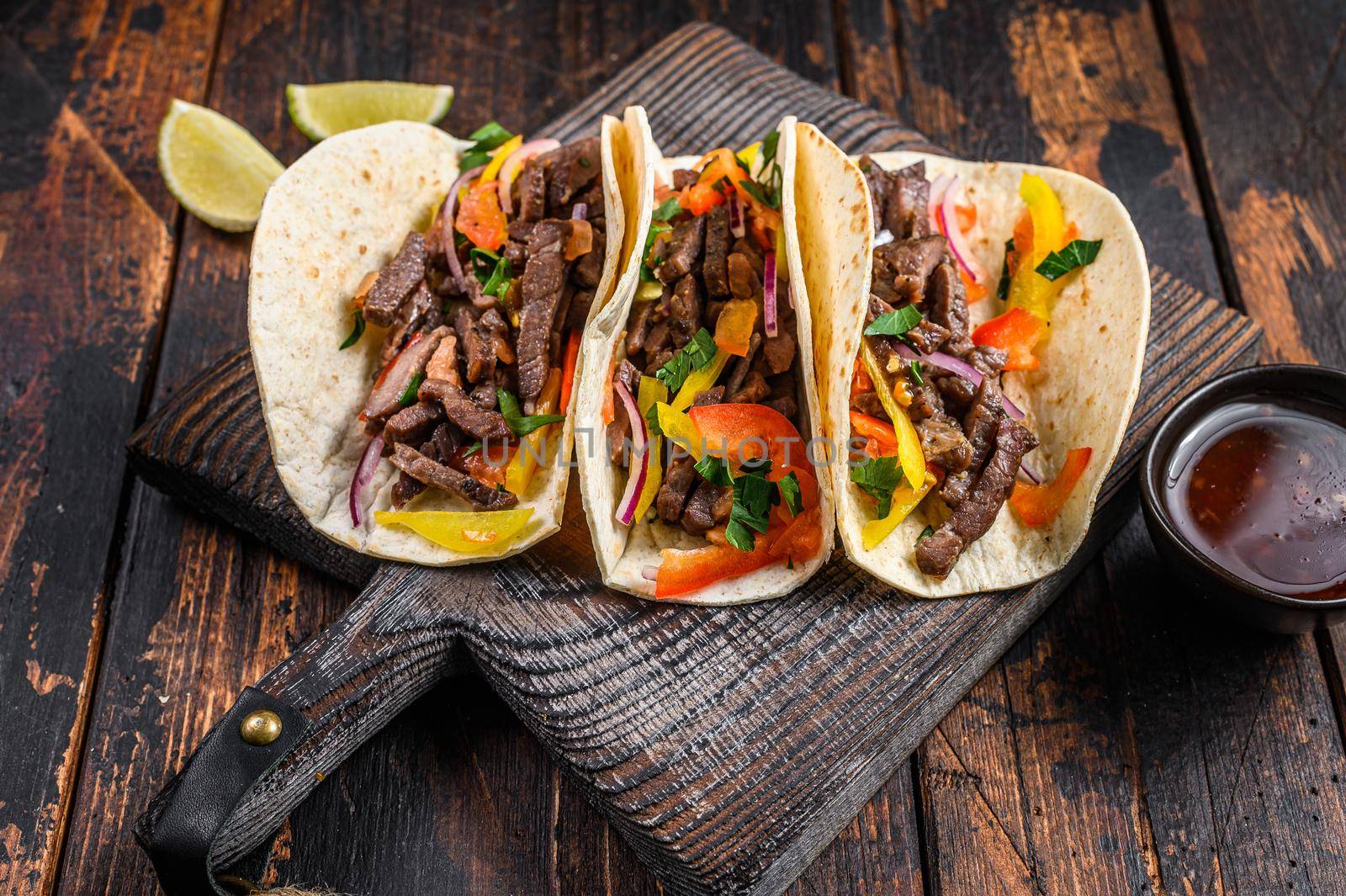 Tacos shells with pork meat, onion, tomato, sweet pepper and salsa. Mexican food. Dark wooden background. Top view.