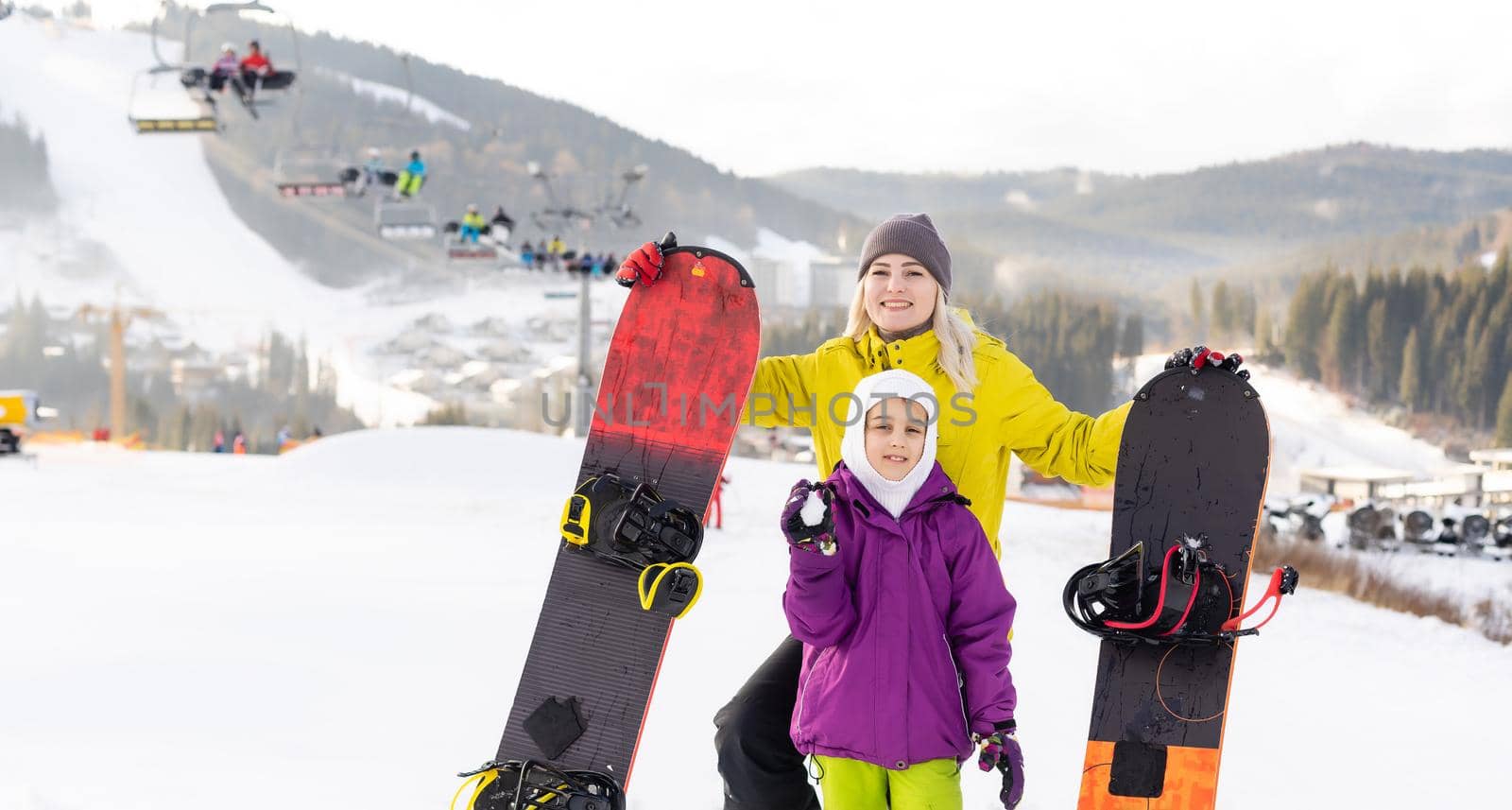 Mother and daughter with snowboards are playing in the snow