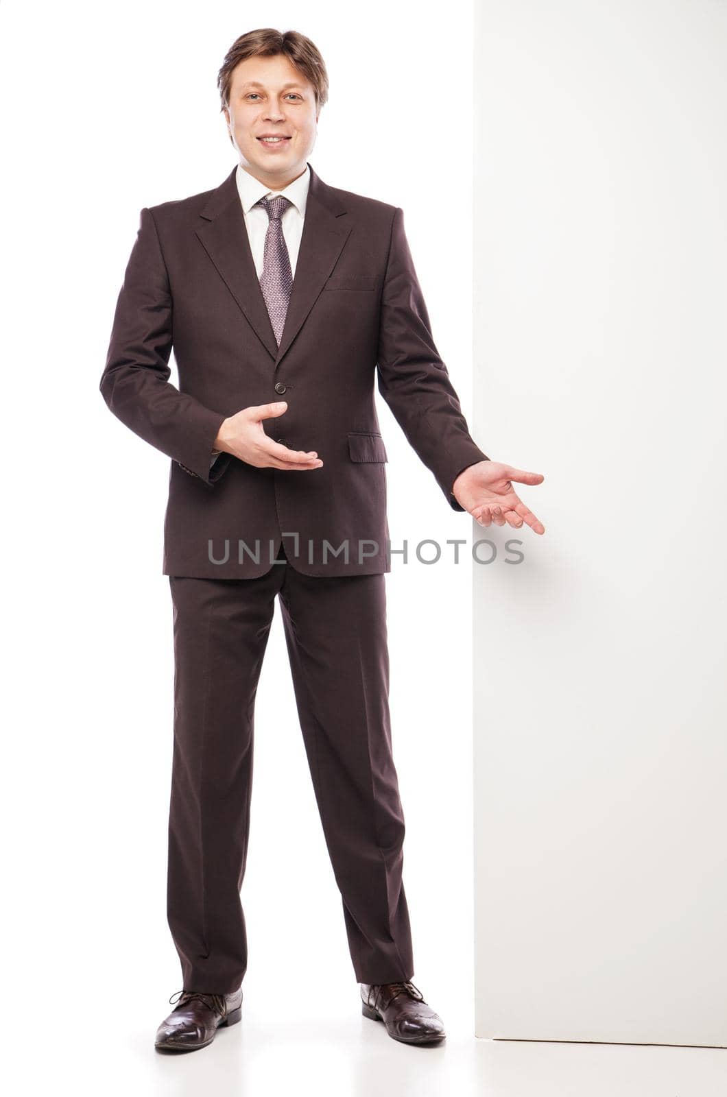 Business man holding empty board and pointing to it while smiling to camera on white background