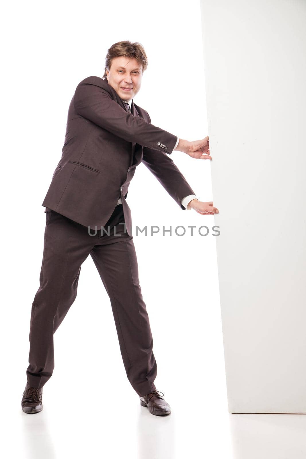 Business man holding empty board and pointing to it while smiling to camera on white background