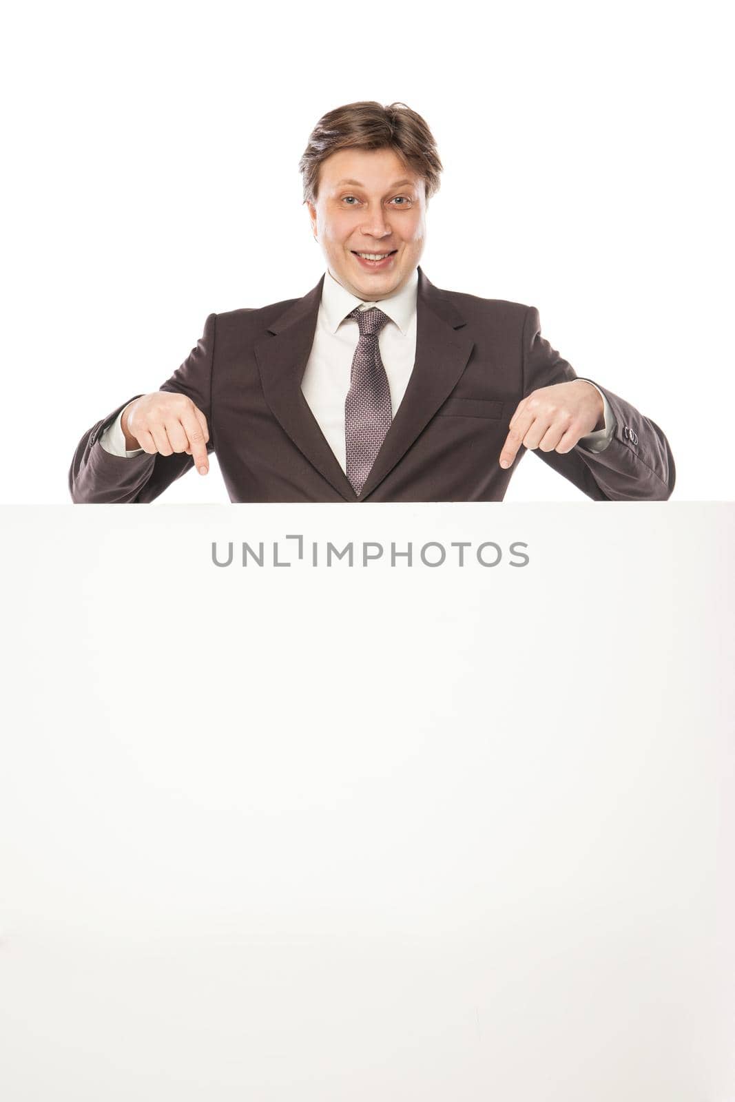 Business man holding empty board and pointing to it while smiling to camera on white background