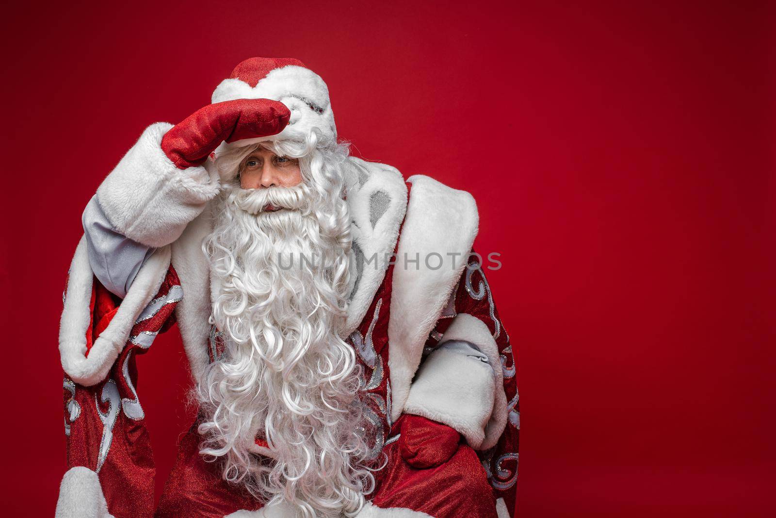 portrait of father frost in long warm coat, red mittens and a hat finds someone by StudioLucky