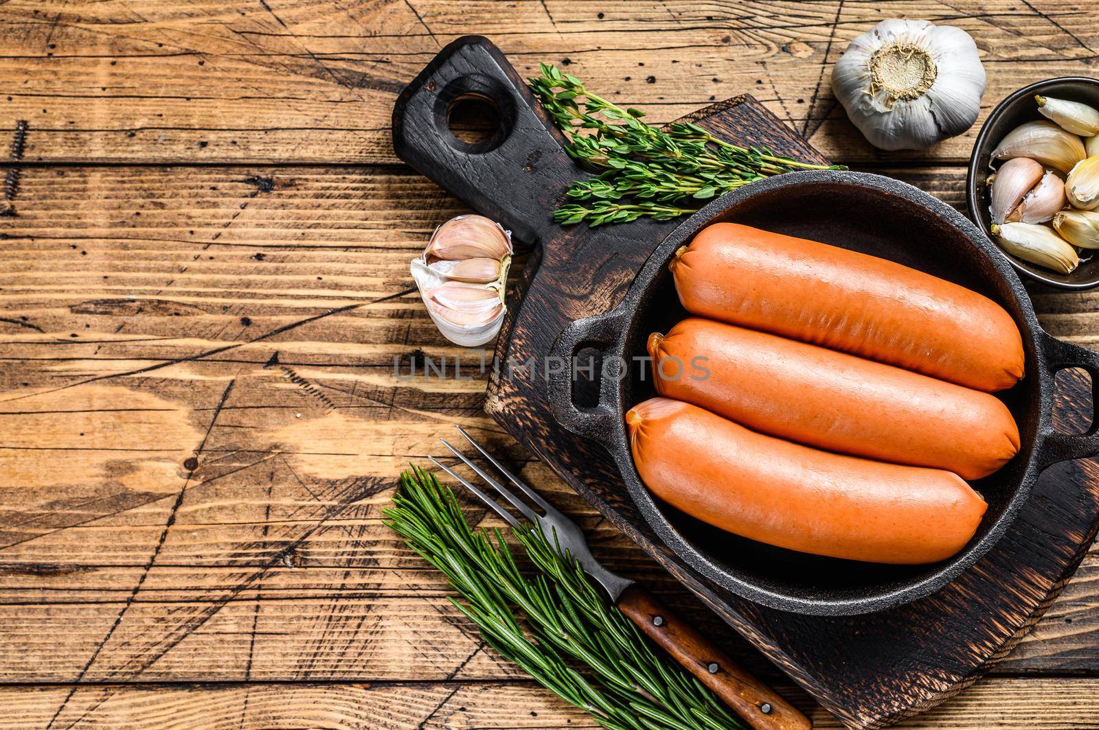 Sausages bratwurst from pork meat in a pan. wooden background. top view. Copy space by Composter